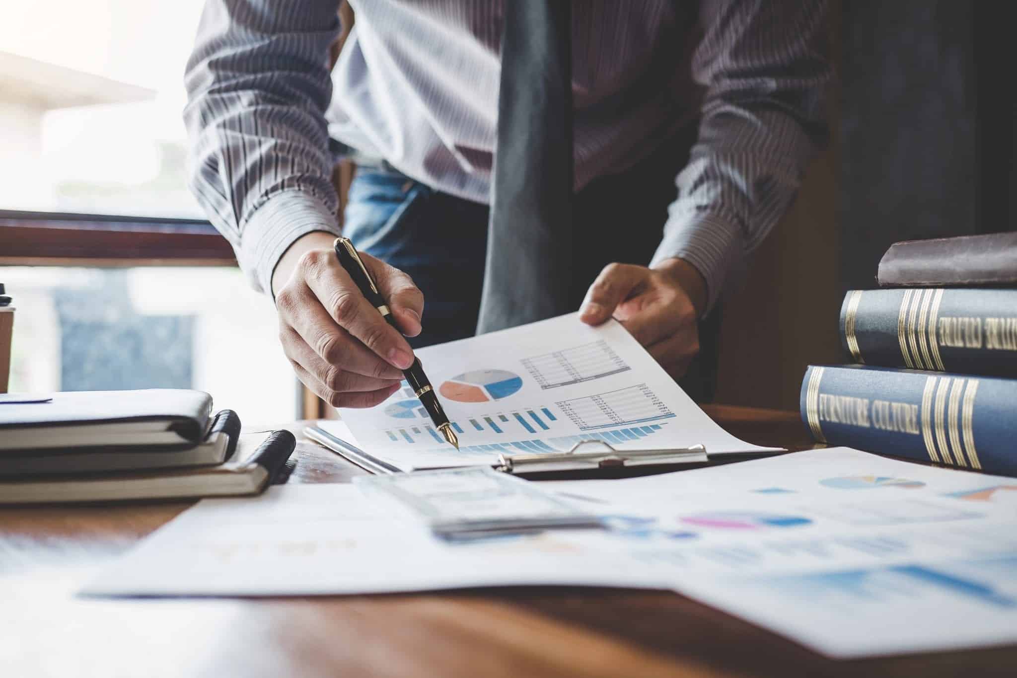 Businessman pointing at graph and chart to analysis use for plans to improve quality, business finances and accounting concept