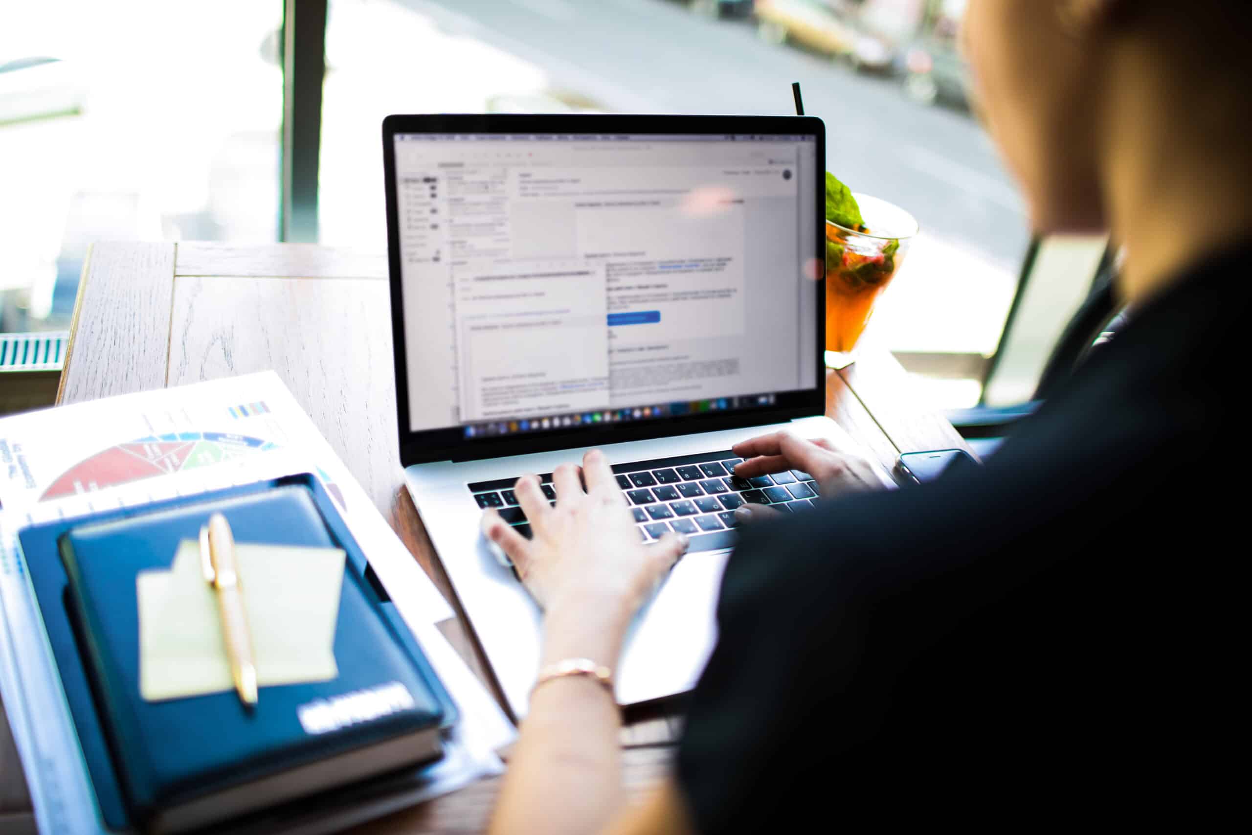 Woman professional business content writer keyboarding on laptop computer, sitting in office interior. Female financier searching information in internet via notebook. Economist using web pages