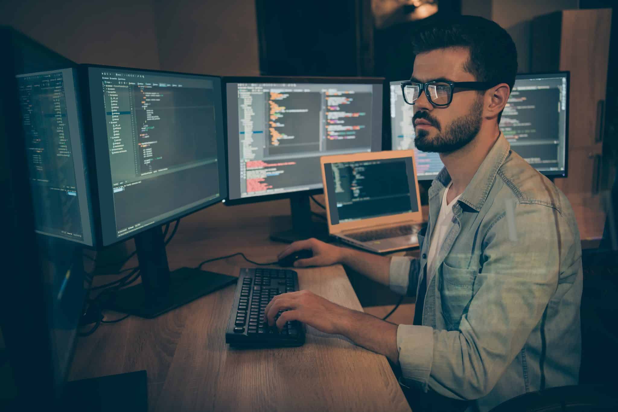 photo a man sitting in front of several computer screens